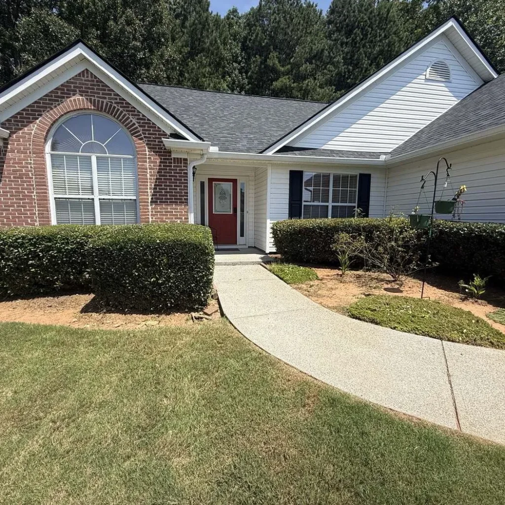 Overgrown front foundation beds and untrimmed shrubs before landscaping work at a Kennesaw home