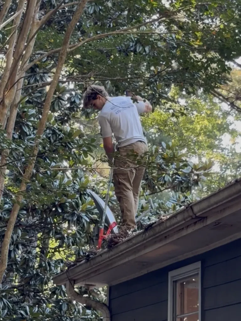 Cleaning gutters on a house under heavy tree cover, where gutters fill several times a year